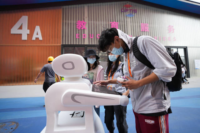 工作人员在服贸会首钢园区调试智能导览交互机器人。新华社发